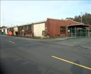 One story brick building along a two lane road. Traffic detour signs alongside the building. 